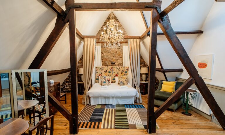 A vaulted attic bedroom with a canopy bed, Huntsham Court
