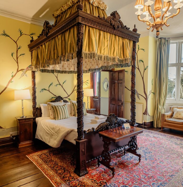 A bedroom with a carved four poster bed and a gold canopy, Huntsham Court