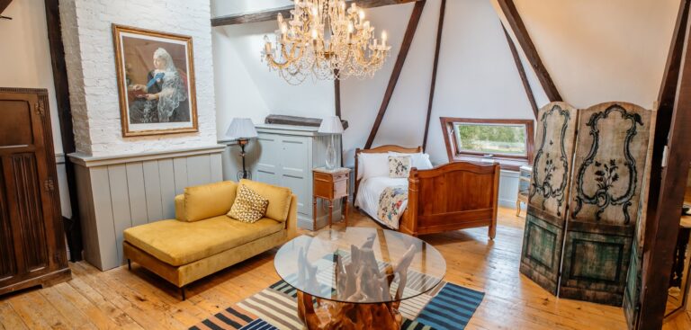 A bedroom with a canopy bed and a sofa seating area, Huntsham Court