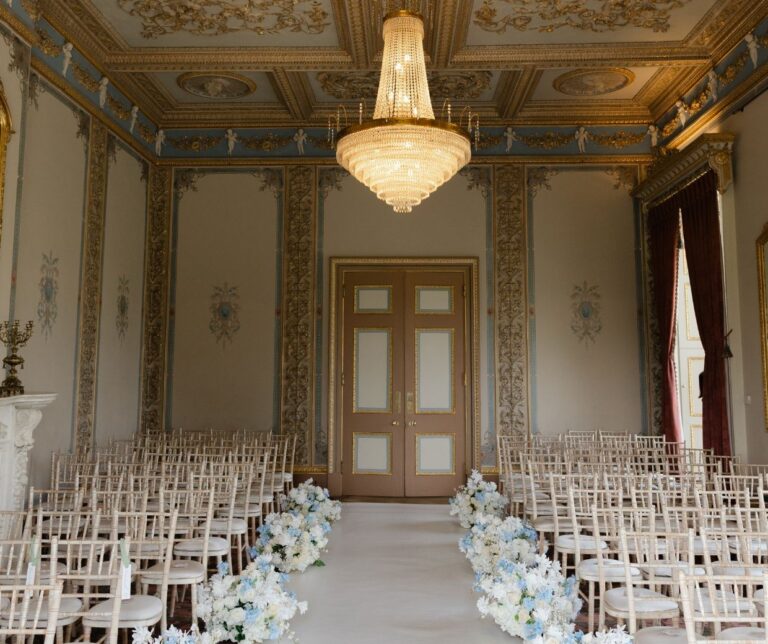 The Drawing Room laid for a civil ceremony, white chairs and a floral aisle beneath the chandelier, Hylands Estate