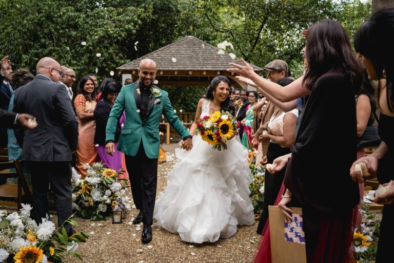 Confetti and sunflower bouquets as the couple leave the ceremony garden, Hylands Estate