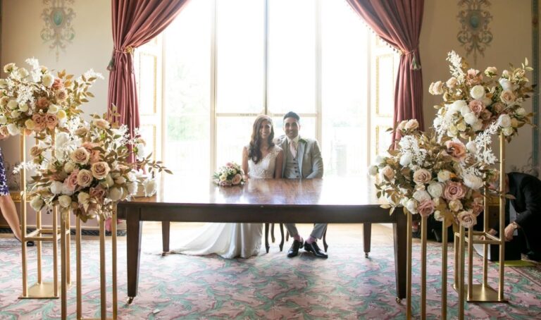 Signing the register at a table framed by tall floral pillars, Hylands Estate