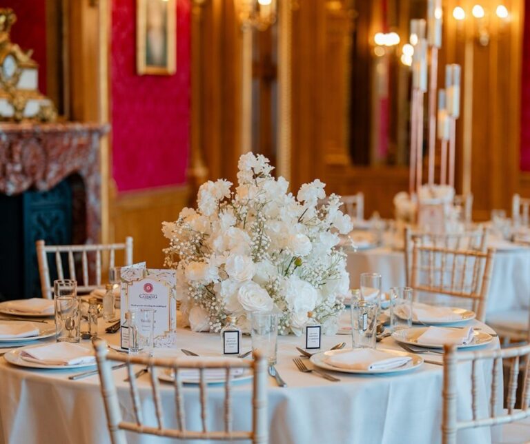 Round tables with white blossom centrepieces in the gilded Banqueting Room, Hylands Estate