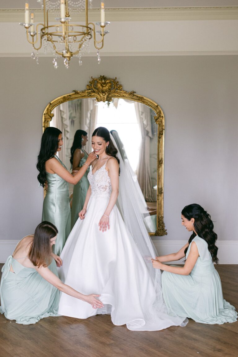 The bride with her bridesmaids at an antique mirror in a wedding suite, Hylands Estate