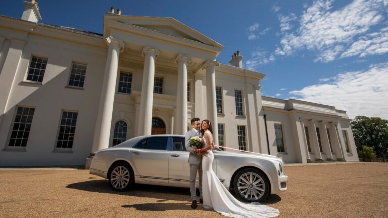 The couple beside a white Rolls-Royce at the columned front entrance, Hylands Estate