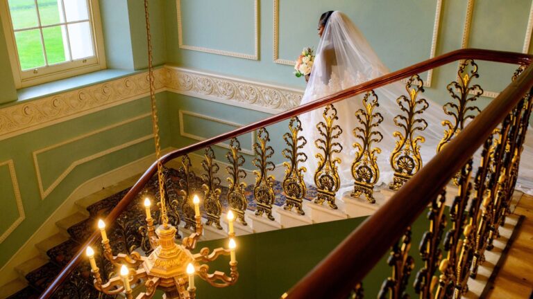 The bride descending the grand staircase, gilt balustrade and chandelier, Hylands Estate