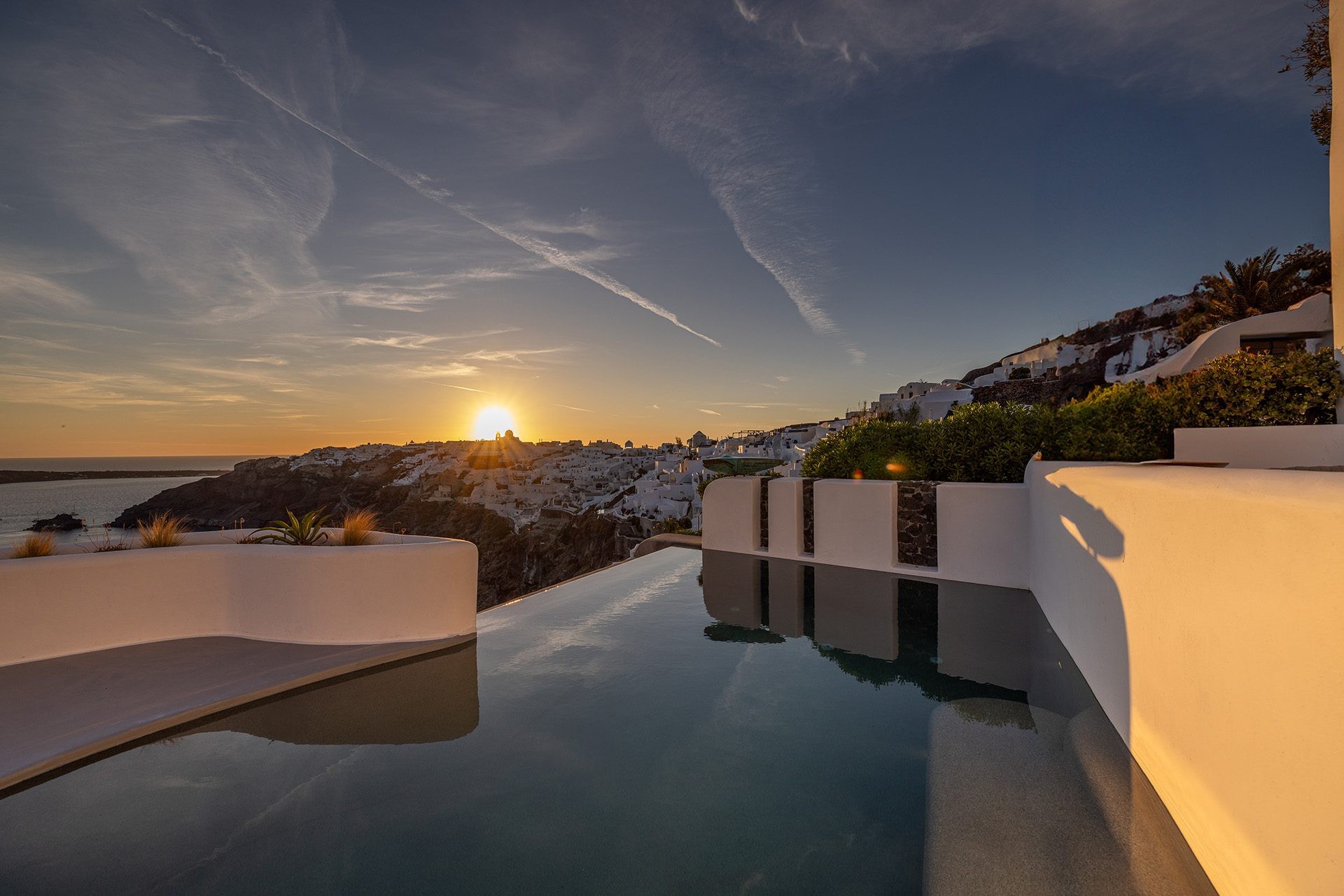Sunset over the cliffs of Oia beside a pool, Ikies Traditional Houses