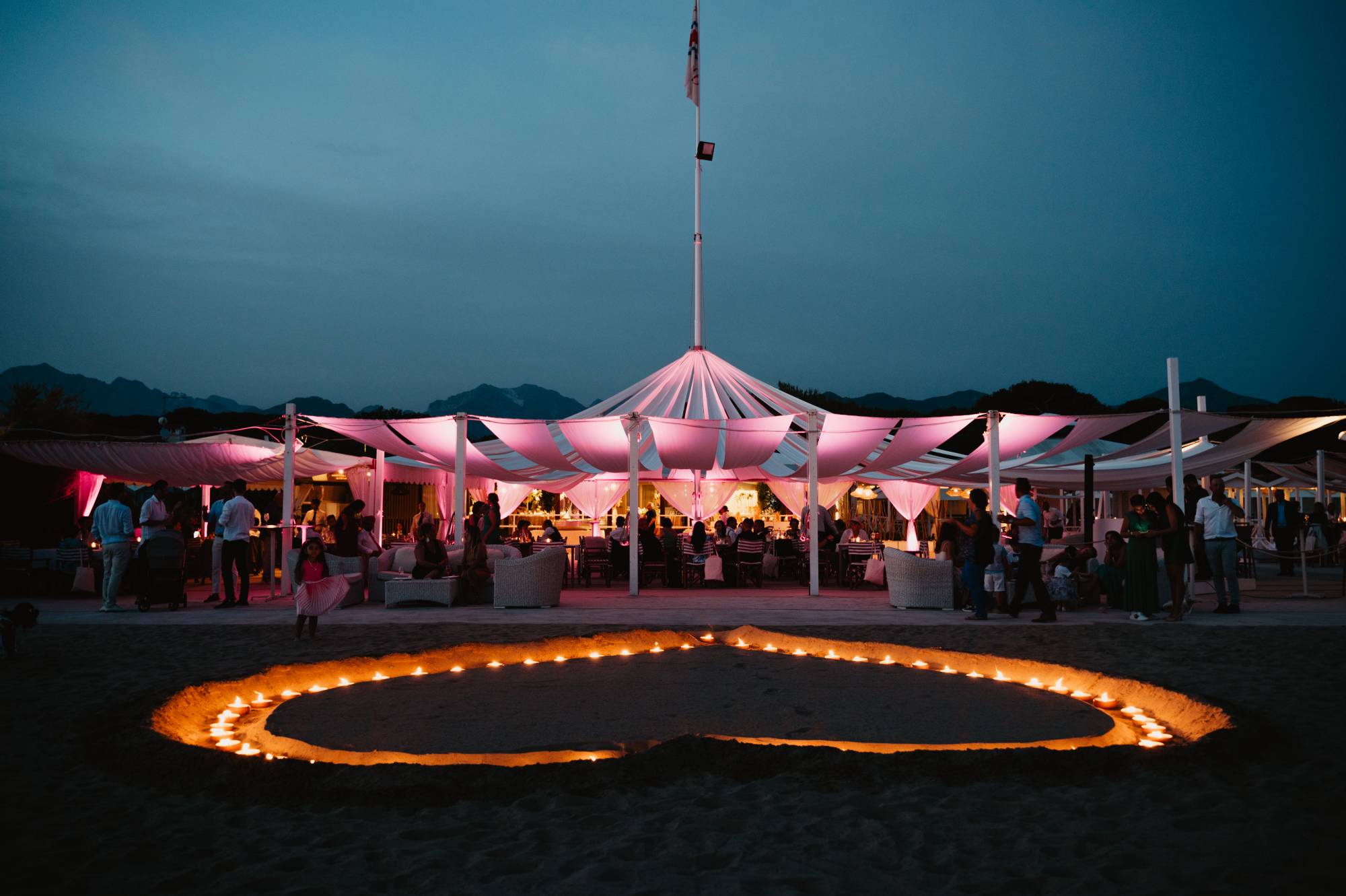 Dusk on the beach: the marquee lit pink and a heart of candles laid out on the sand, Il Giorno Perfetto di Glenda Marradi