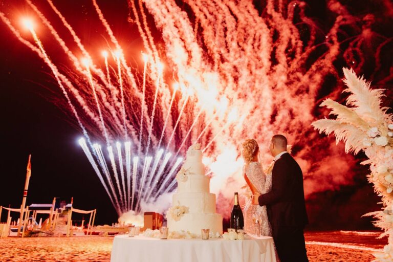 Cutting the cake on the beach at night against a wall of red firework fountains, Il Giorno Perfetto di Glenda Marradi
