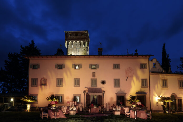 A Tuscan villa at blue hour, its tower lit and dinner tables laid on the lawn below, Il Giorno Perfetto di Glenda Marradi