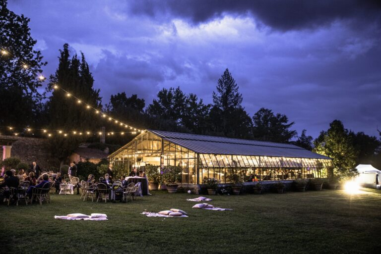 Guests on the lawn at dusk outside a lit glasshouse, festoon lights overhead, Il Giorno Perfetto di Glenda Marradi