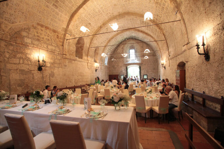 Dinner under a stone barrel vault, lit by wall sconces, for Deniz and Justin's wedding in Umbria, Il Mio Matrimonio