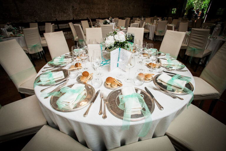 A round table laid with silver chargers and mint-green ribbon, for Deniz and Justin's wedding in Umbria, Il Mio Matrimonio