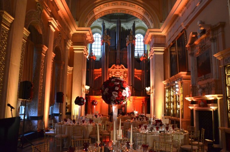 A grand hall dinner table, red and purple roses beneath a gilded organ case, In Water Flowers