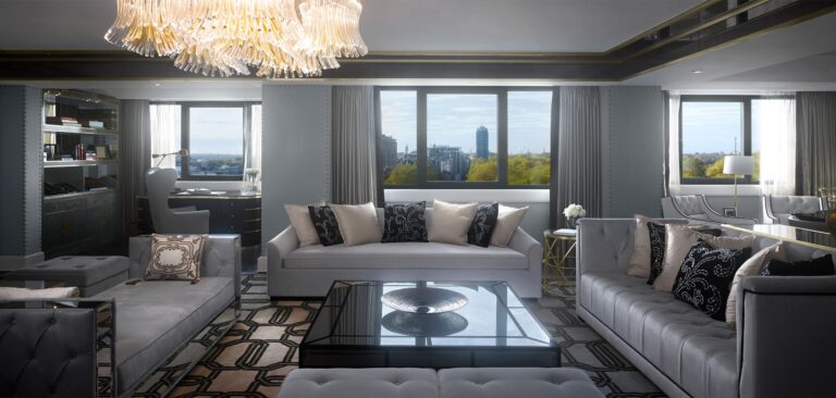 The Royal Suite living room, with grey sofas, a crystal chandelier and windows over the trees of the Royal Parks, InterContinental London Park Lane