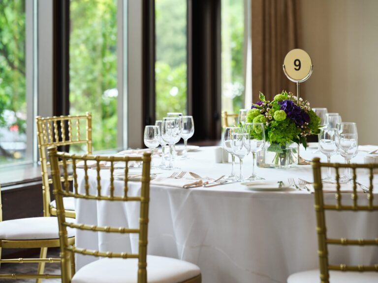 A round table by a window laid with glassware, a numbered table marker and a green and purple posy, InterContinental London Park Lane