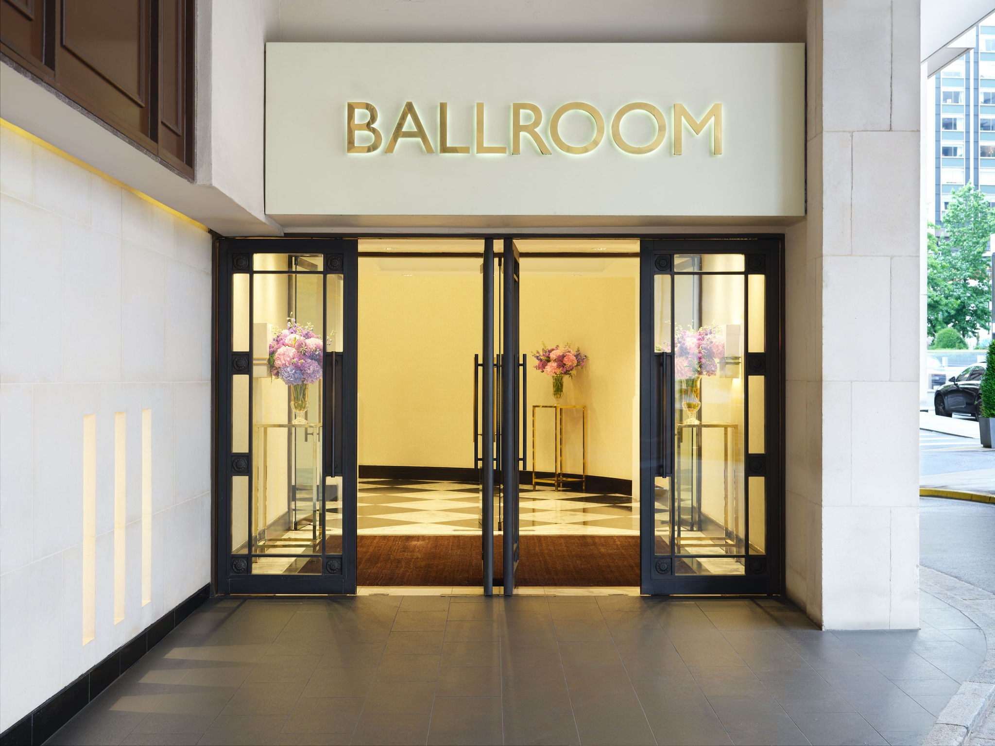 The Ballroom's own glass-doored entrance on Hamilton Place, lit from within and flanked by floral arrangements, InterContinental London Park Lane