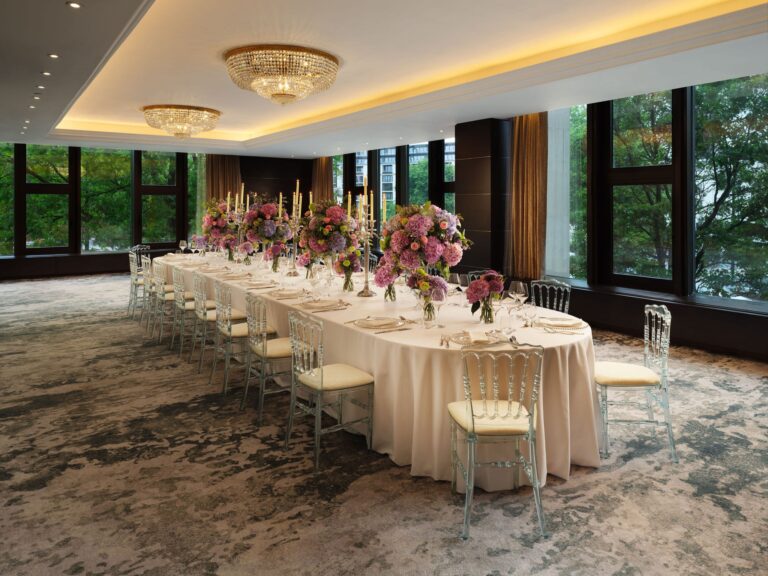 A long banquet table with tall pink and purple arrangements in the Grays suite, with windows along one wall, InterContinental London Park Lane