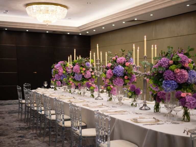 A long table with ghost chairs, silver candelabra and hydrangea arrangements in a private event room, InterContinental London Park Lane
