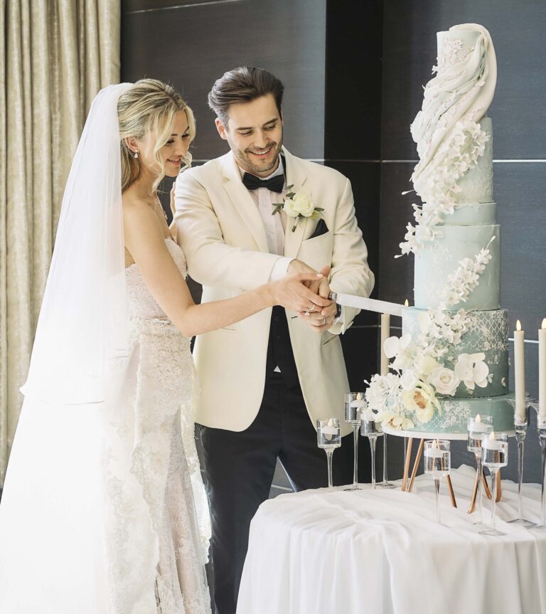 A couple cutting a tall pale green cake decorated with sugar flowers, InterContinental London Park Lane
