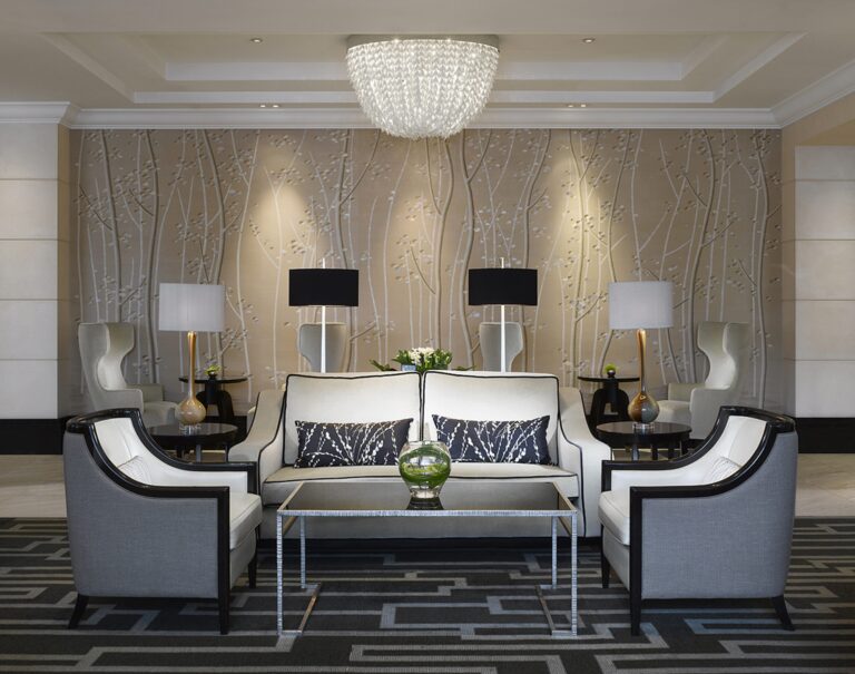 The Wellington Lounge, with a crystal chandelier over paired sofas and armchairs and a tree-patterned wall, InterContinental London Park Lane