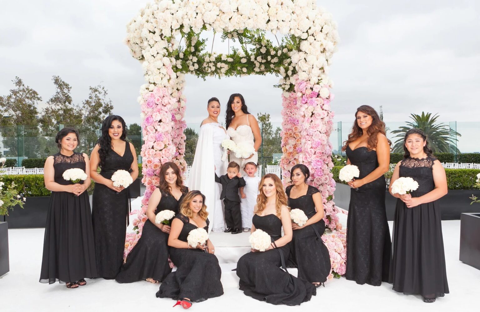 A bridal party in front of a pink and white floral canopy, International Event Company