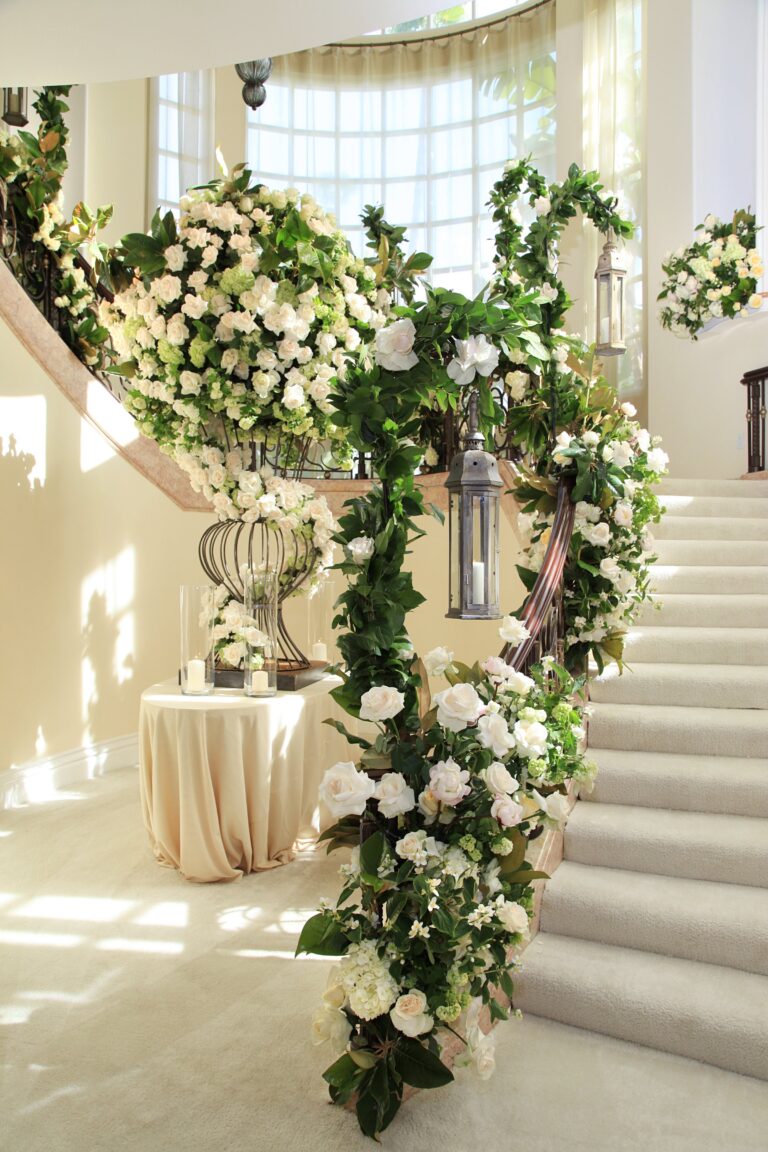 A curved staircase wound with a garland of white roses and greenery, International Event Company