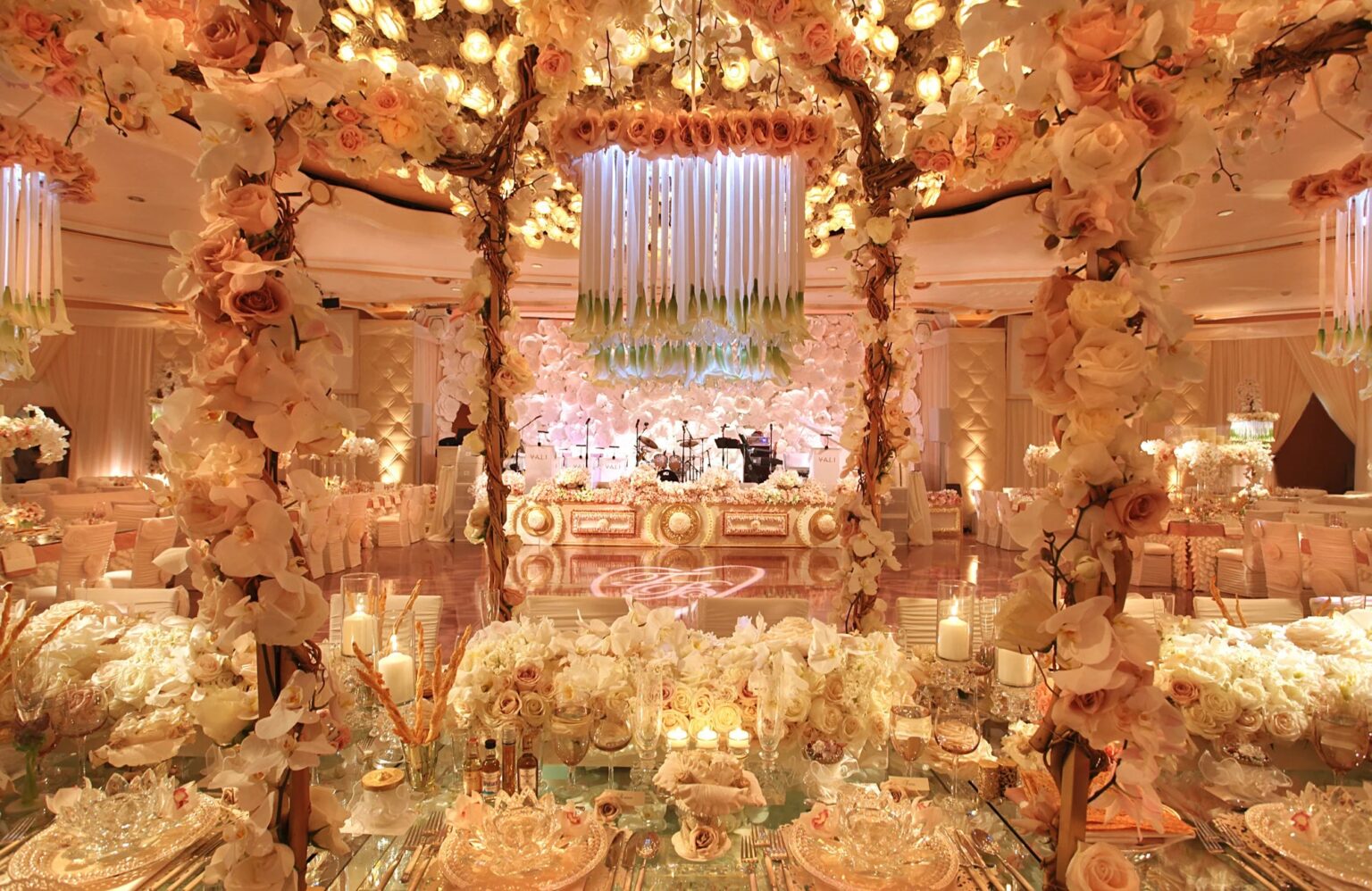 A reception under a canopy of blossom with chandeliers, glowing in warm light