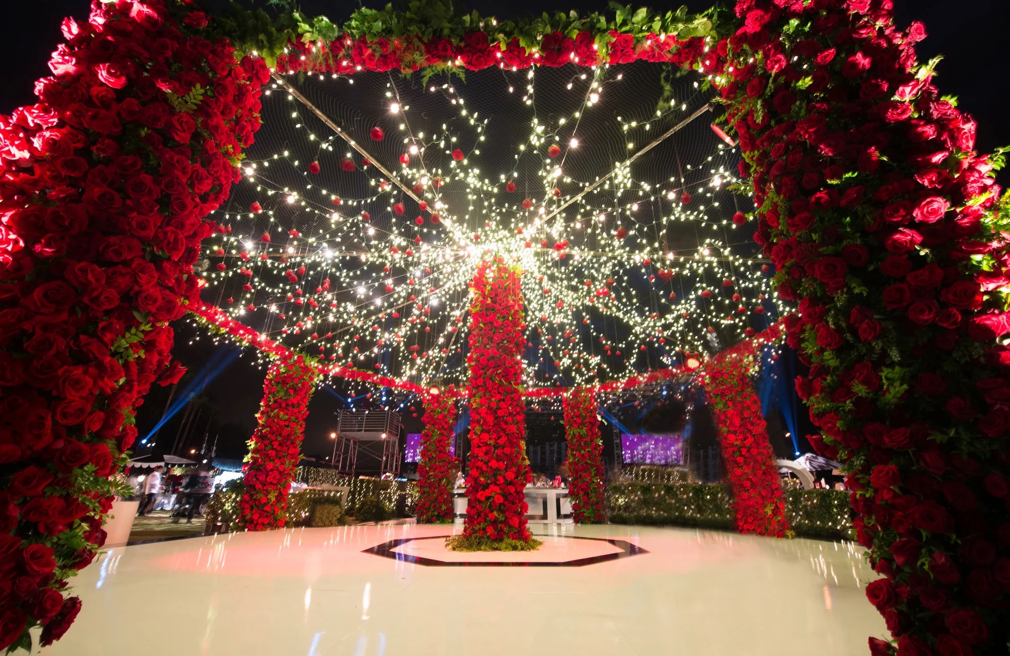 A red rose canopy hung with lights over a white dance floor at night, International Event Company