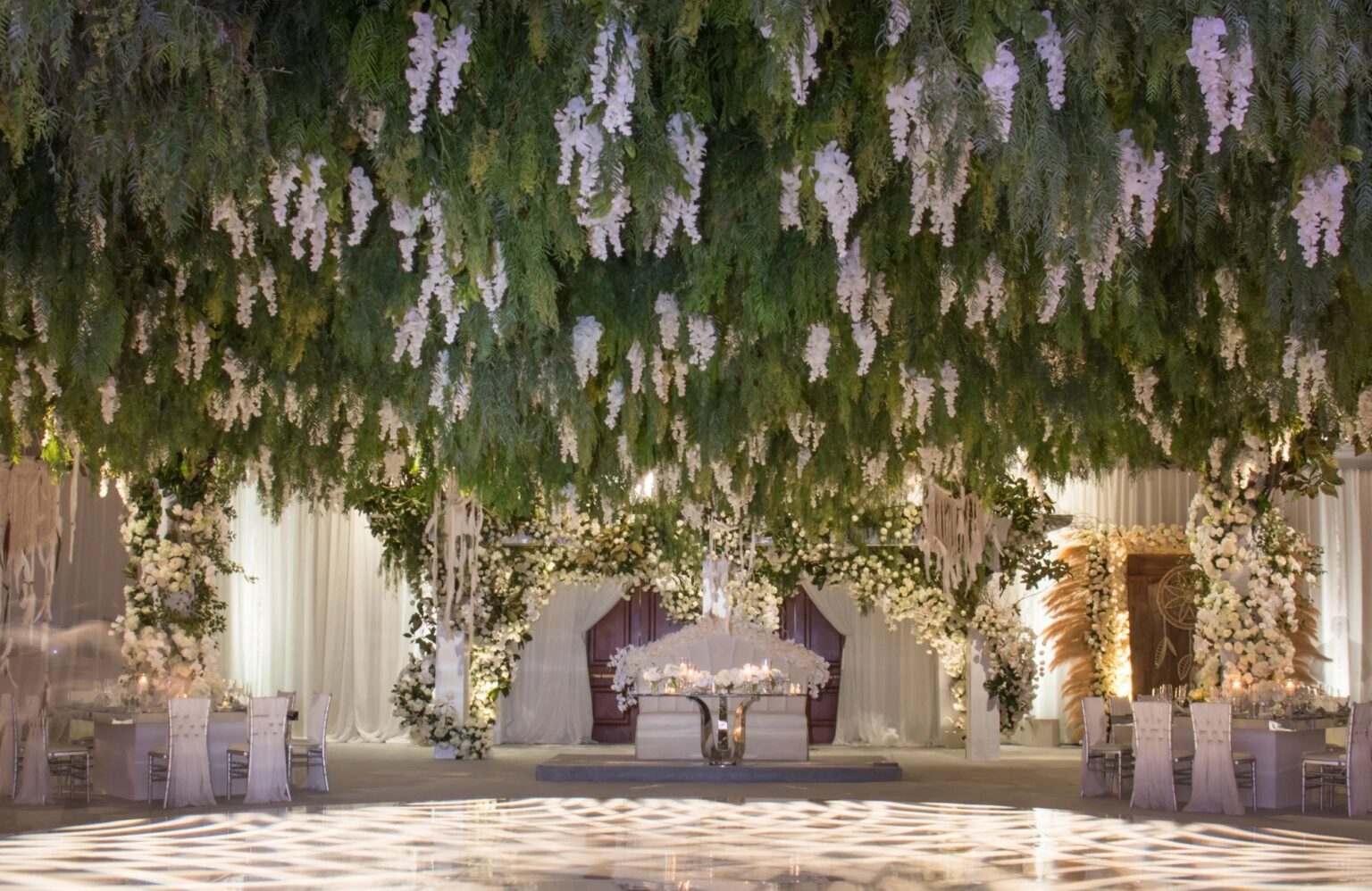 A ballroom ceiling covered in hanging wisteria above a patterned dance floor