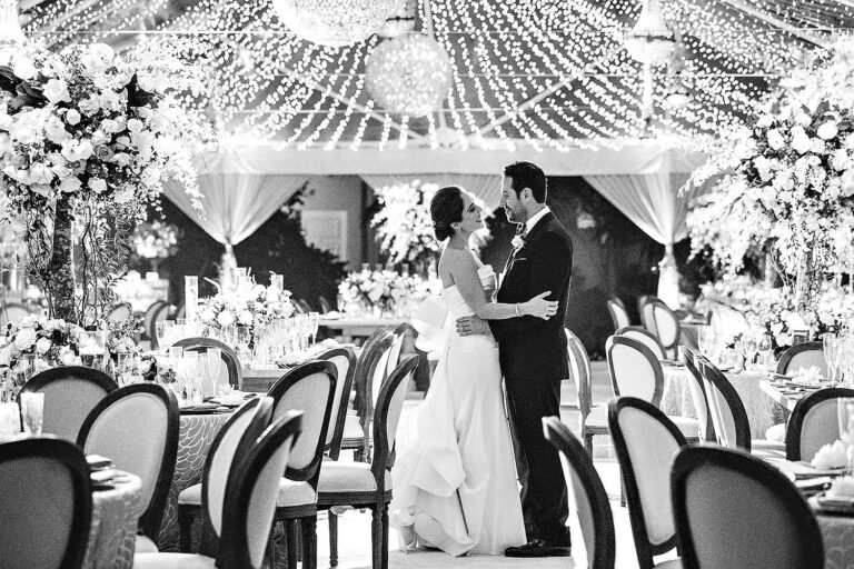A couple dancing in a tent under strung lights, in black and white, International Event Company