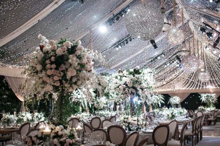 A tented reception with crystal orbs, floral centrepieces and round tables, International Event Company