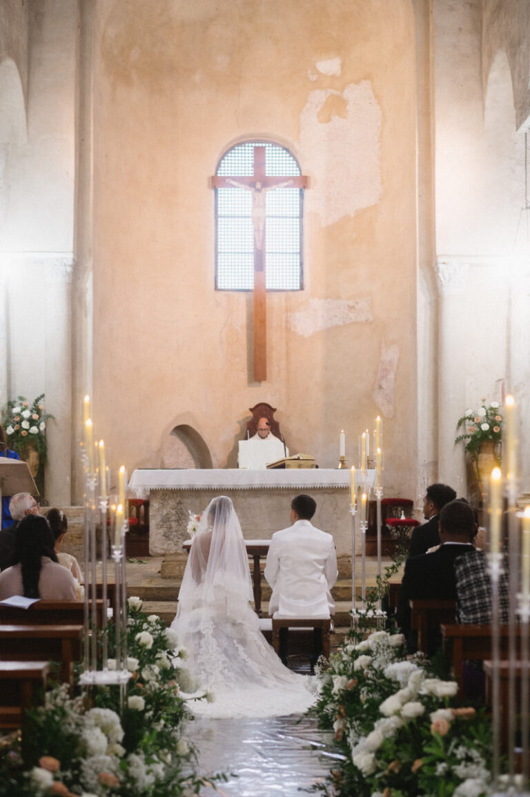 The church ceremony, candles and white flowers lining the aisle to the altar, Iole Criscitiello