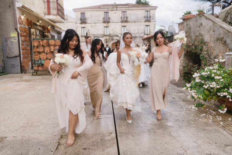 The bride and her bridesmaids, in blush and ivory, walking through the town streets, Iole Criscitiello