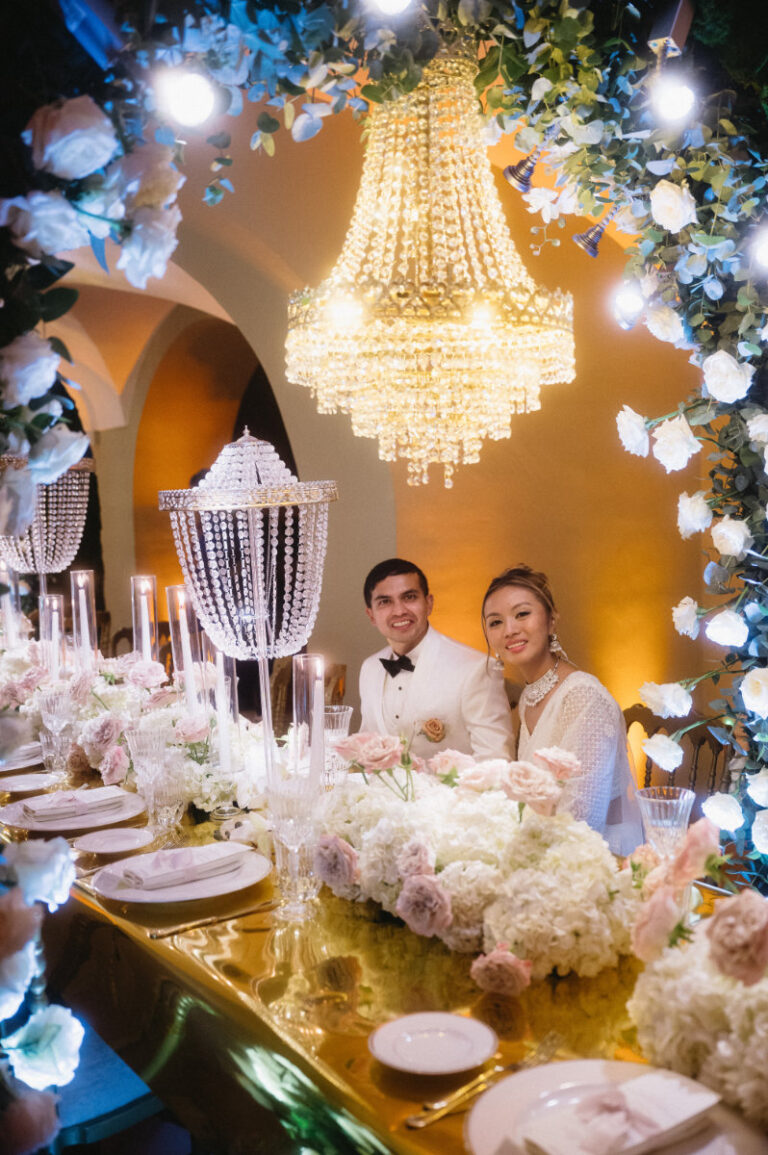 The couple at the head of the table, white flowers piled the length of it, Iole Criscitiello