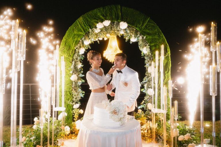 Cutting the cake under a green and white floral arch between sparkler fountains, Iole Criscitiello