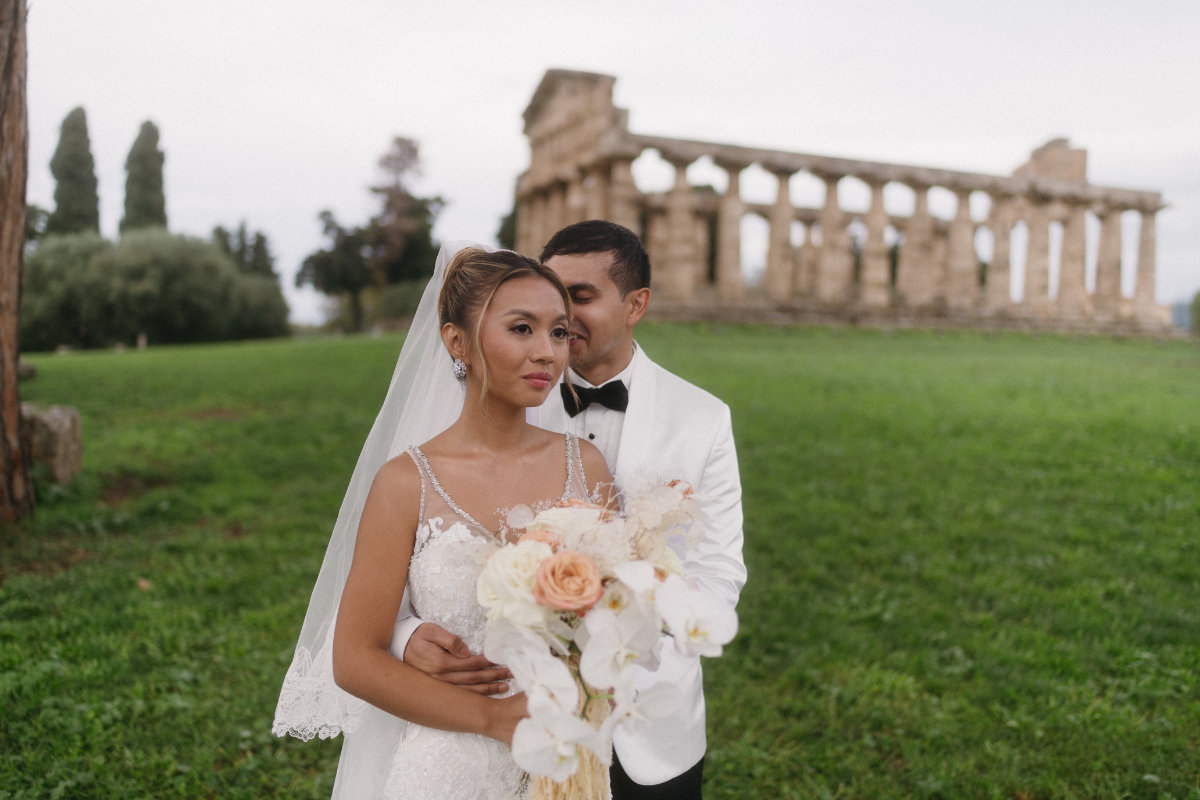 The couple on the grass at Paestum, the temple colonnade behind them, Iole Criscitiello