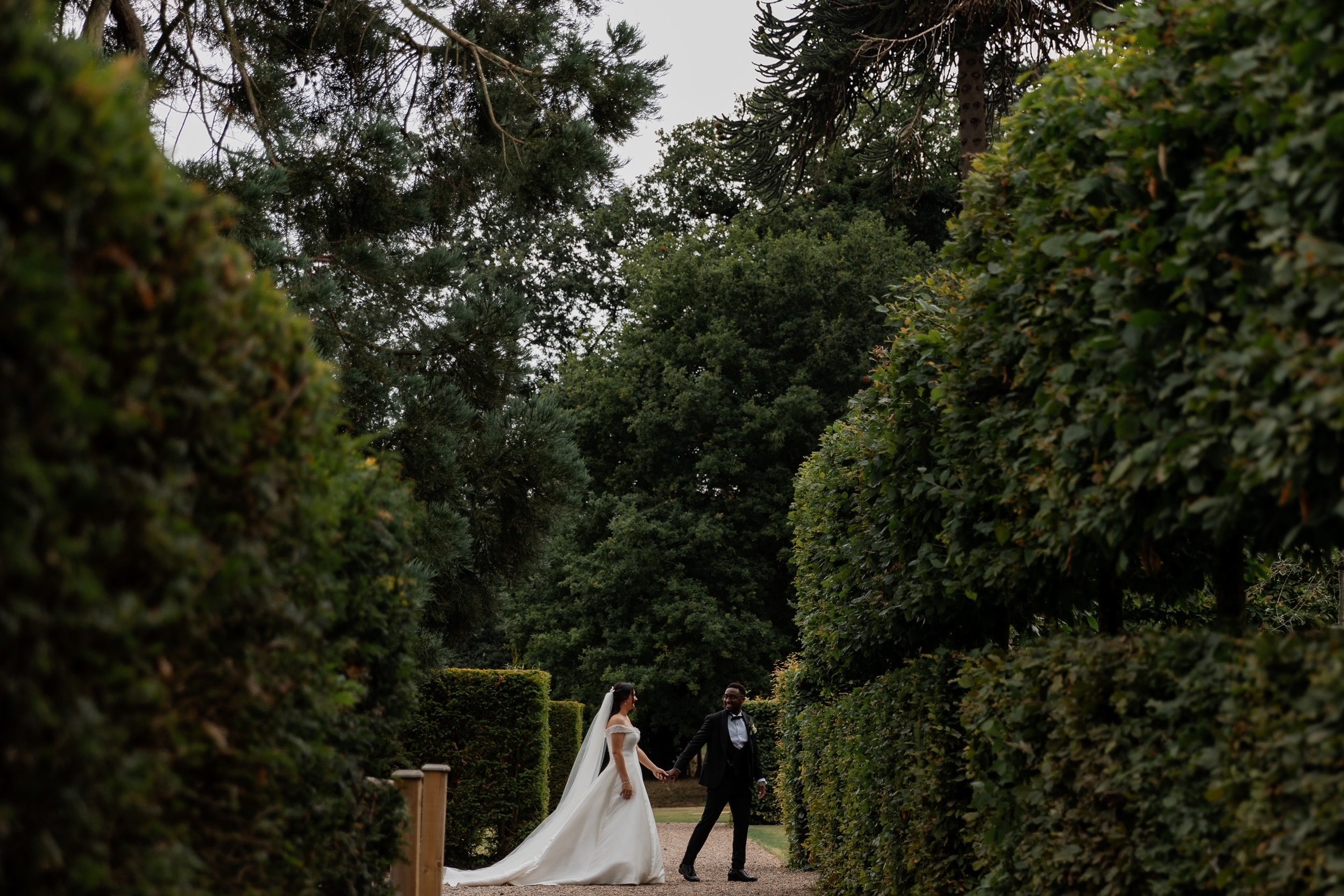 A couple almost lost among the tall clipped hedges of the gardens, Iscoyd Park