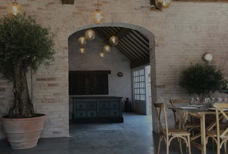 The Coach House interior, exposed brick, a potted olive tree and tables laid for a gathering, Iscoyd Park