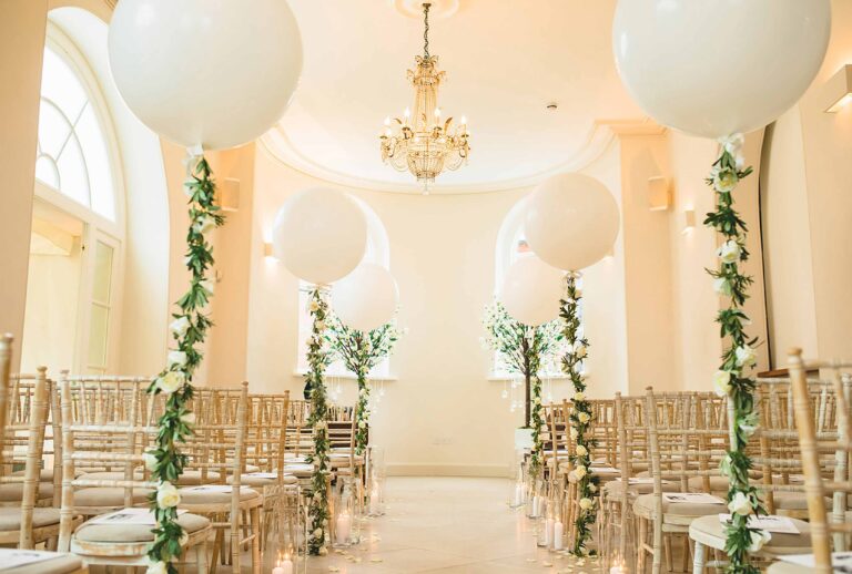 The Garden Room dressed for a celebration with hanging orbs, chandeliers and greenery-wrapped columns, Iscoyd Park