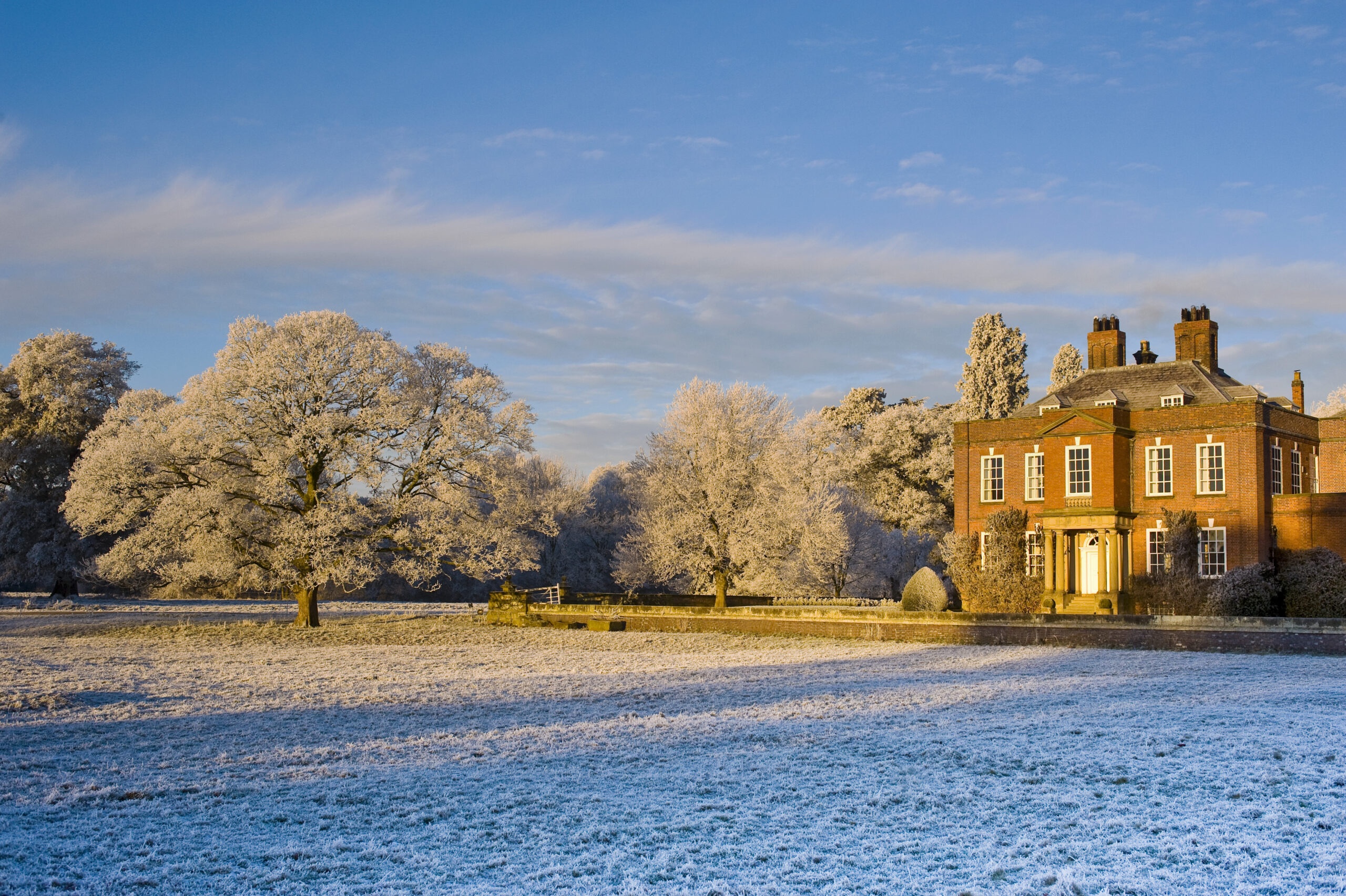 The house across frosted parkland on a winter morning, a snow-covered tree in the foreground, Iscoyd Park