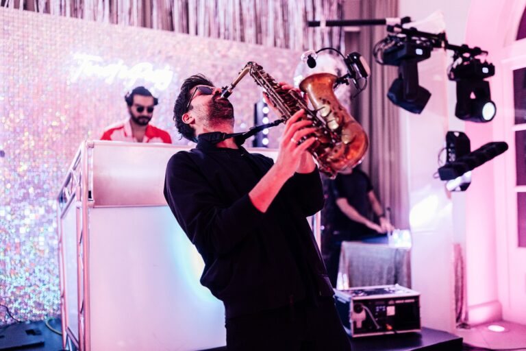 A saxophonist plays alongside the DJ booth as the party gets under way, Iscoyd Park