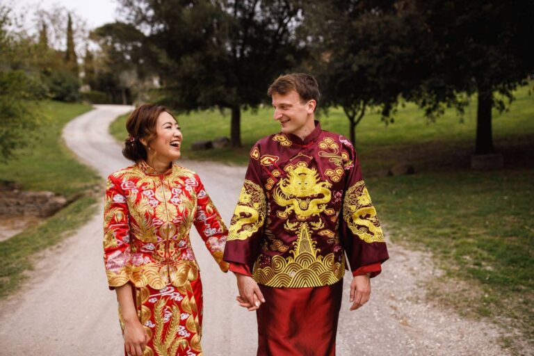 A couple in traditional Chinese wedding dress, walking a gravel drive through a Tuscan park, Italian Event Planners