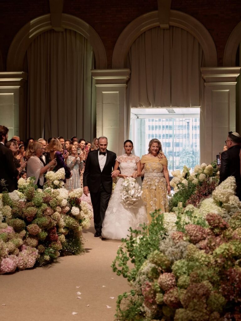 A bride on her father's arm along a hydrangea-lined aisle, Italian Eye