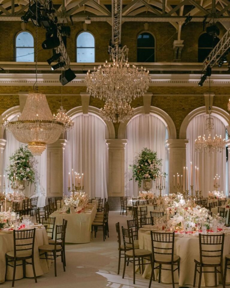 A ballroom reception with two tiers of crystal chandeliers over round tables, Italian Eye