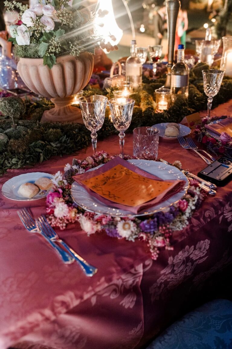 A place setting ringed with a dried-flower wreath on rose-red damask linen, Italian Eye