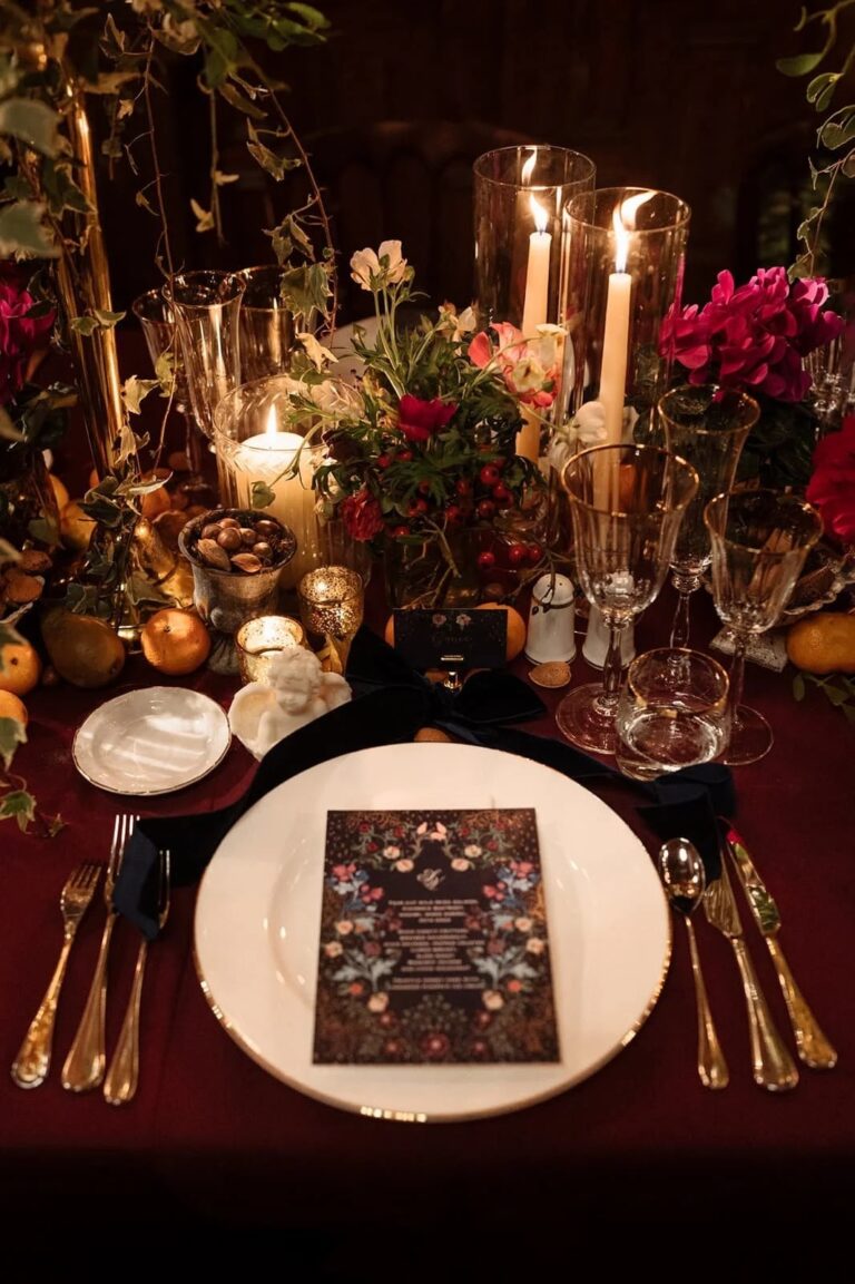 A burgundy place setting with a dark botanical menu card, candles and clementines, Italian Eye