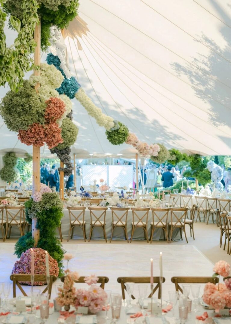 Inside a sailcloth marquee with columns wrapped in hanging hydrangea globes, Italian Eye