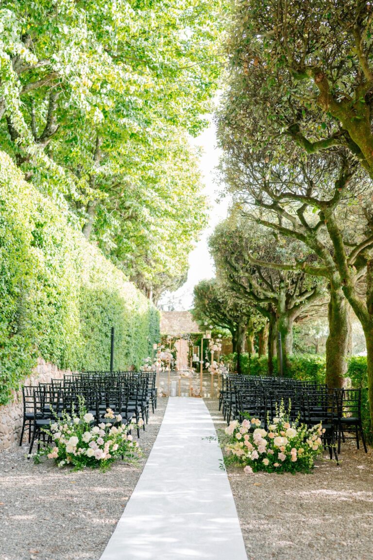 Aisle between rows of chairs and flower arrangements in a hedged garden, Tuscany, Italian Wedding