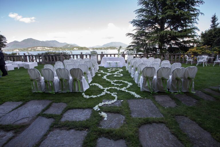 Chairs dressed in white either side of a petal-strewn aisle on the lawn of Villa Claudia dal Pozzo, Lake Maggiore, Italian Wedding Company